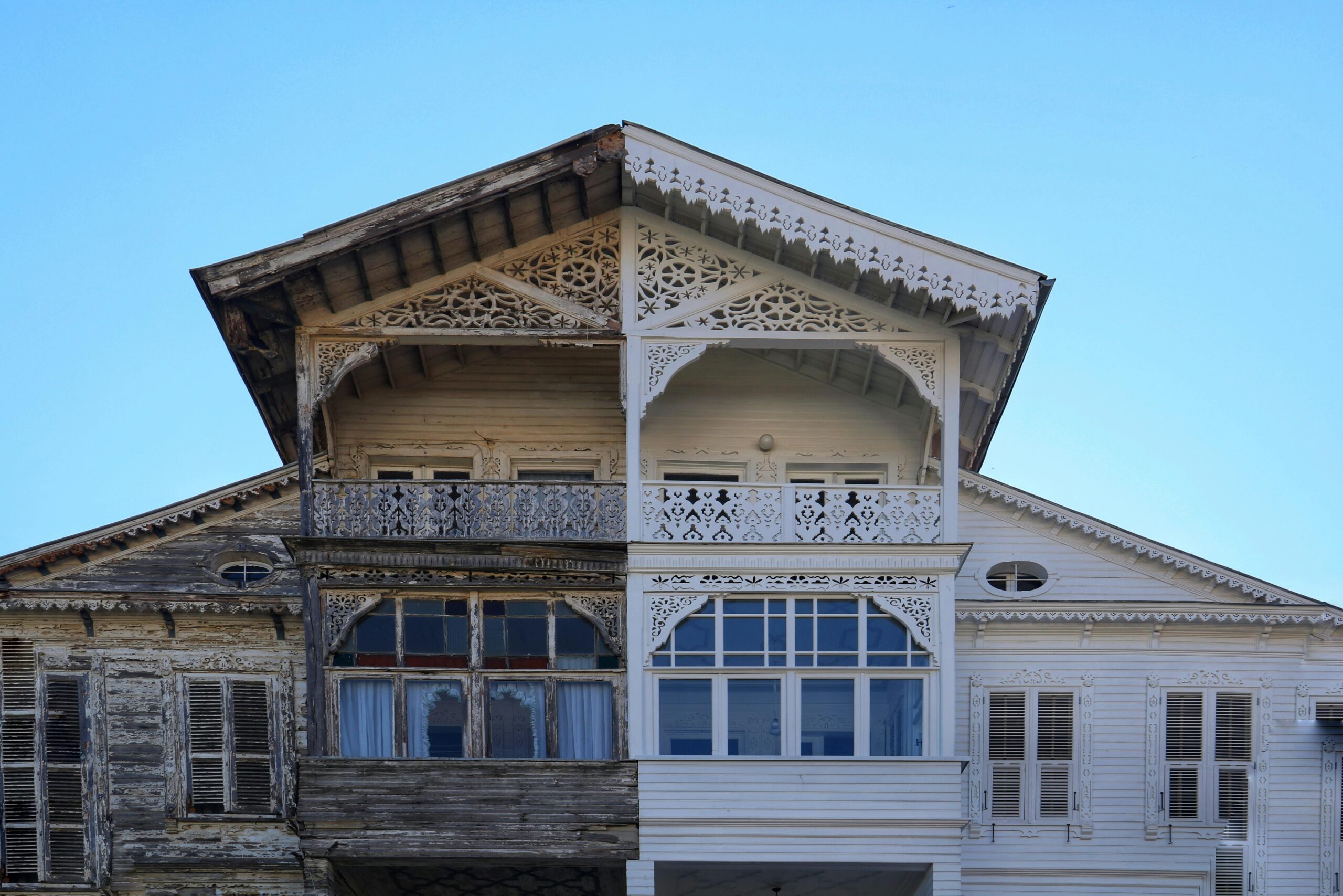 A detailed view of a half-renovated wooden house facade, showing old vs new.