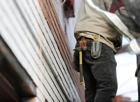 Close-up of a construction worker with hammer and tools, focused on the job.